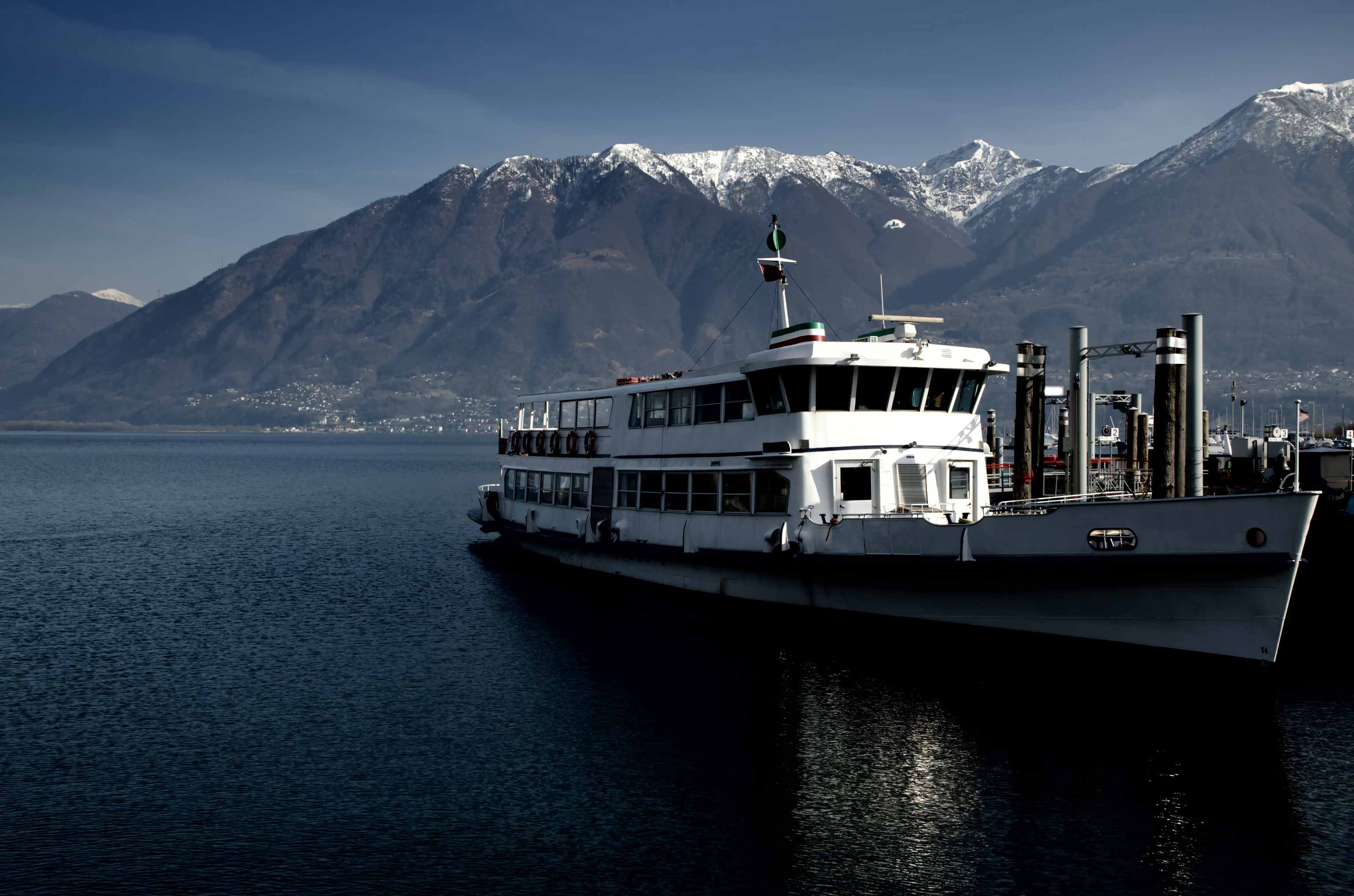 yacht-sea-surrounded-by-hills-covered-greenery-snow-sunlight