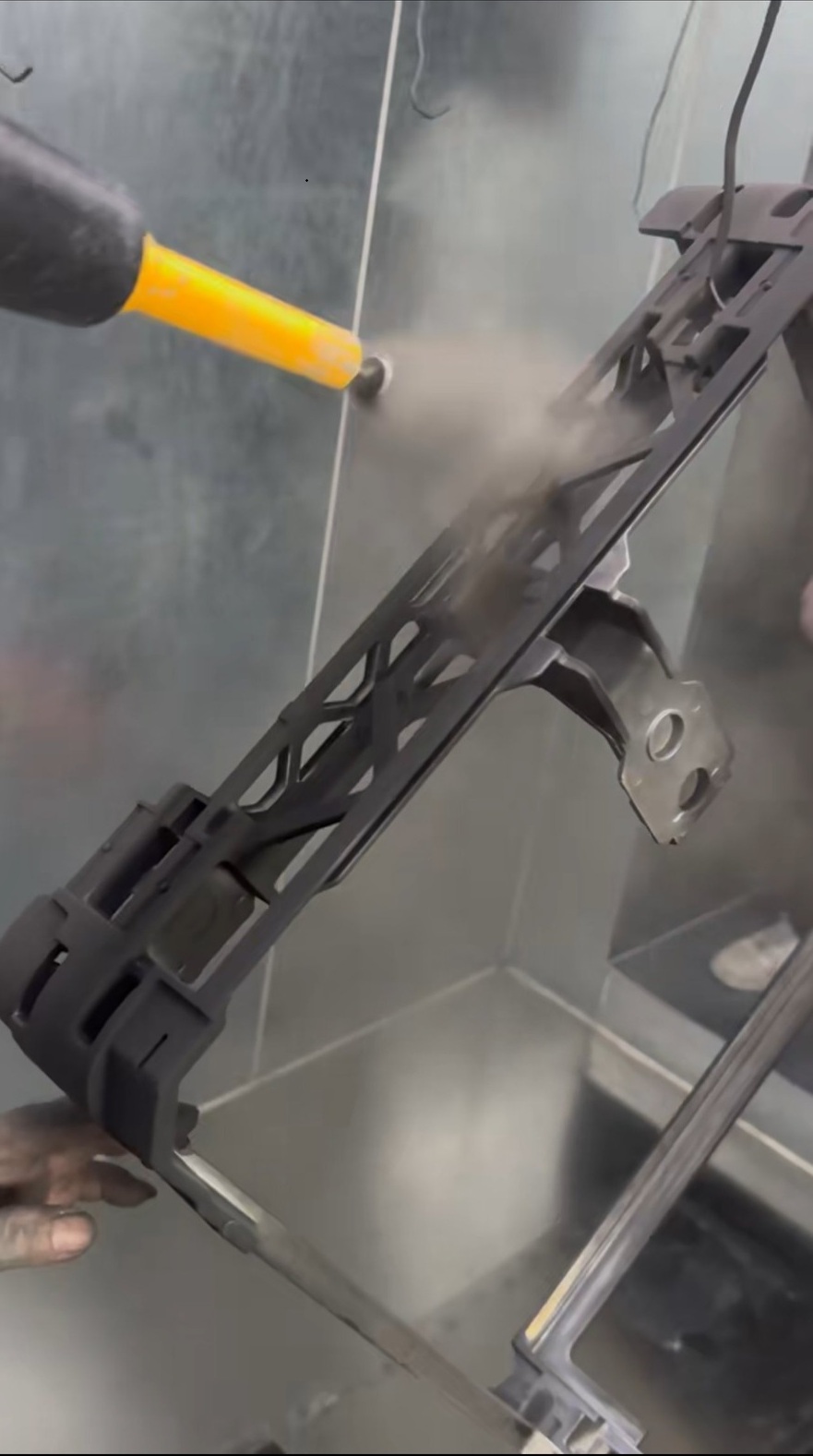 Complex automotive bracket showing typical Faraday cage failure—standard powder guns leave recesses and internal channels uncoated
