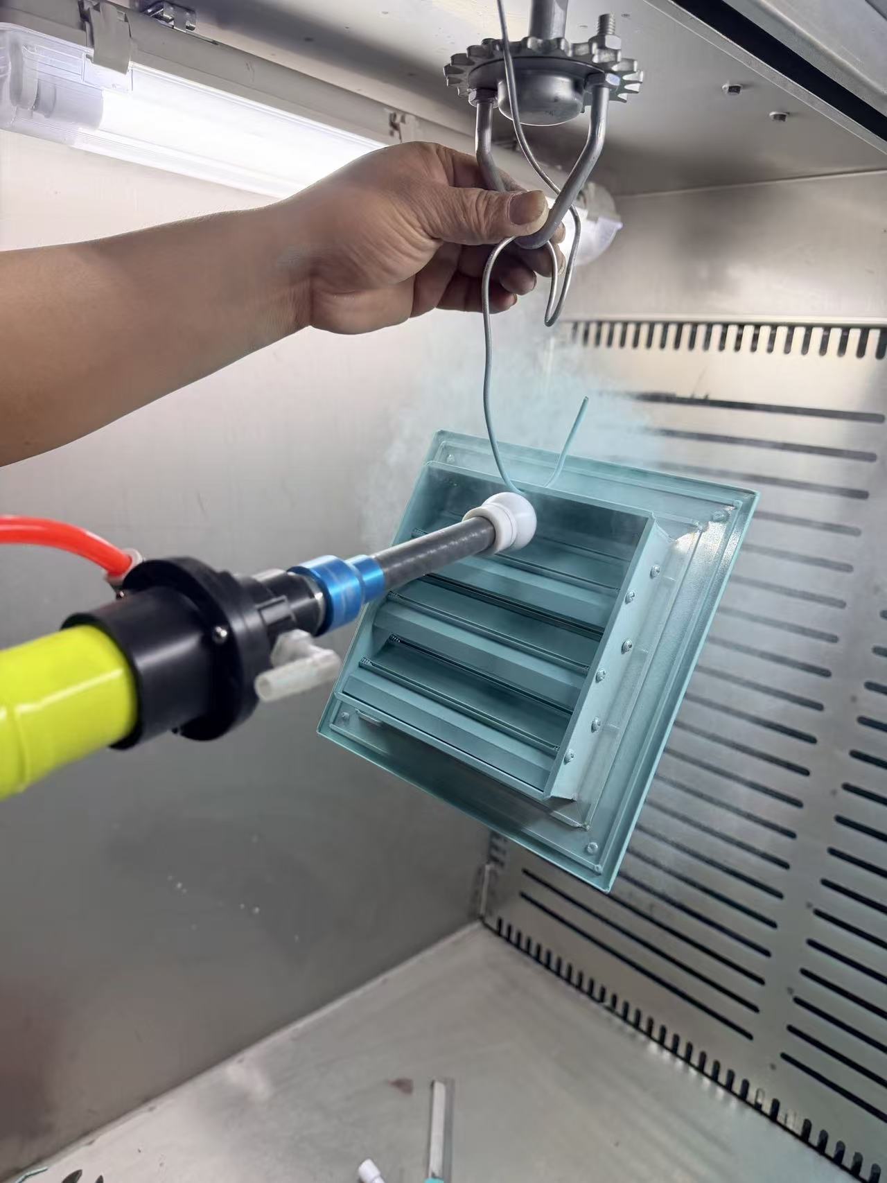 Q7 powder coating gun spraying HVAC diffuser with complex internal geometry