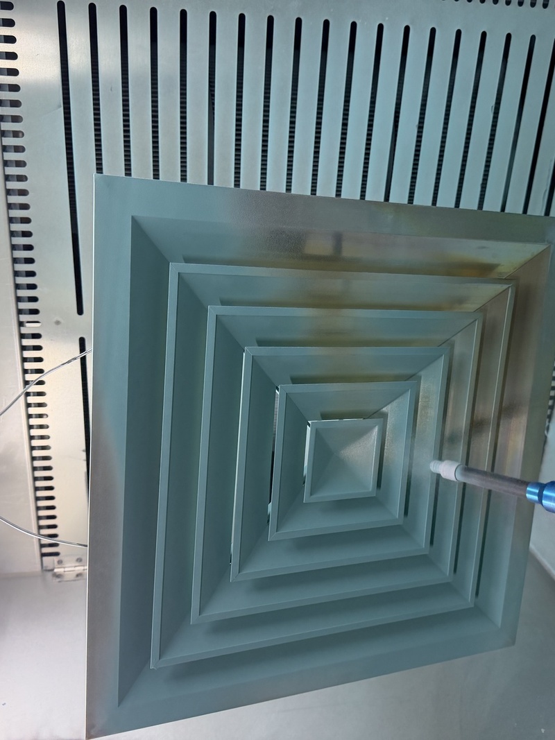 Q7 handheld powder coating gun coating a square ceiling air diffuser with five concentric recessed layers — a textbook Faraday cage geometry where standard guns fail, exported to Europe and North America